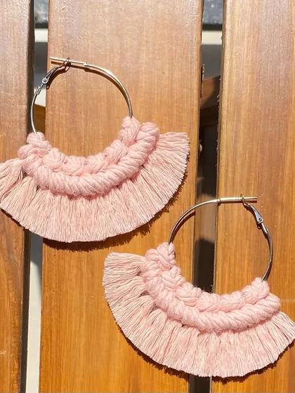 A product shot of our boho fringe earrings against a wooden background. The contrast highlights the soft texture and intricate knotting of the pink macrame.