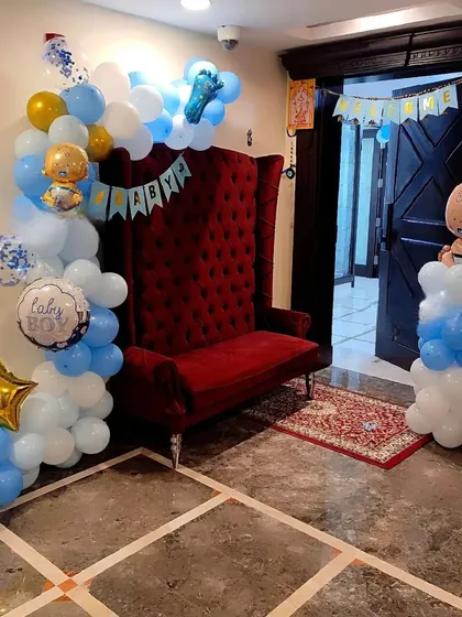 A simple yet elegant welcome home setup. I used a red high-back chair as a focal point, framed with a blue and white balloon arrangement and a 'BABY' banner.