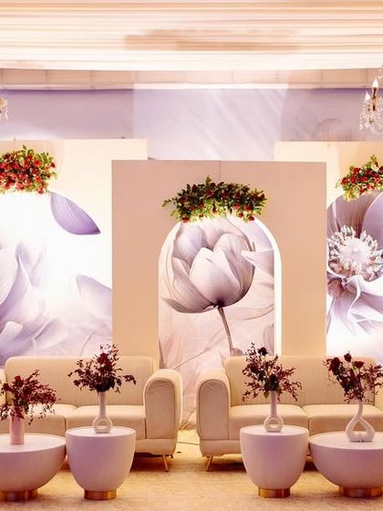 A stylish photo backdrop featuring modern arches with large-scale monochrome floral prints, topped with fresh red and green floral arrangements.