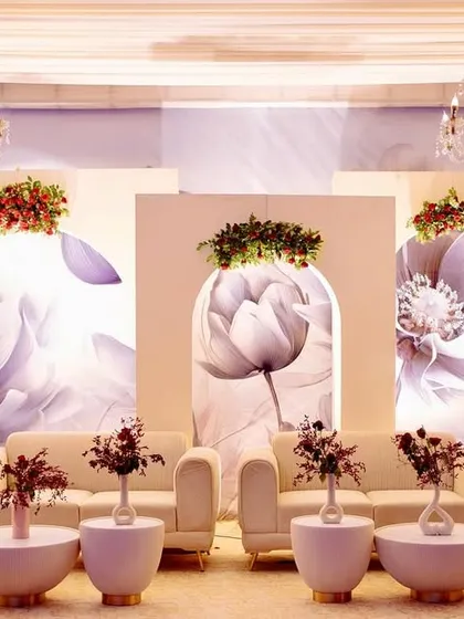 A stylish photo backdrop featuring modern arches with large-scale monochrome floral prints, topped with fresh red and green floral arrangements.