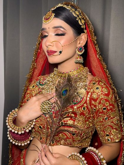 A close-up of a bride with a peacock feather, highlighting her beautiful eye makeup and the intricate details of her jewelry.