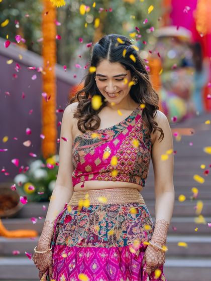 A bride is showered with petals during her Mehendi, a candid moment of pure happiness and vibrant color.