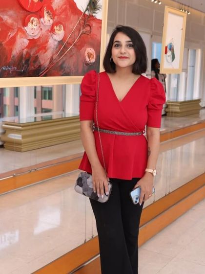 A stylish visitor enjoying the 'Ethereal Charm' exhibition, with a vibrant red artwork in the background.