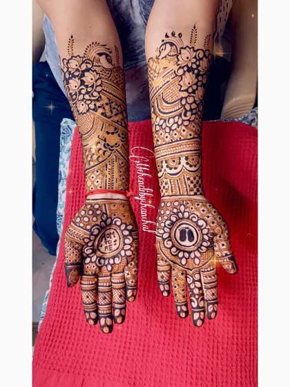 A beautiful baby shower mehendi with tiny baby feet in a central mandala, surrounded by heavy floral and net patterns.