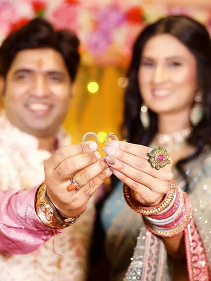 The moment of exchange. This photo focuses on the couple holding up their engagement rings, a clear and joyful symbol of their new beginning.