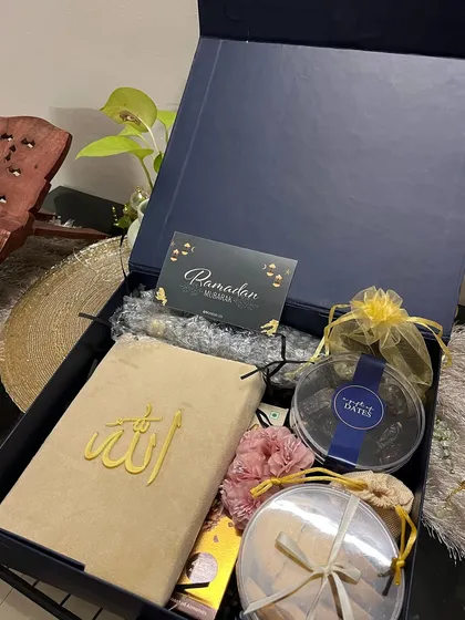 A deep blue luxury box curated for Ramadan, containing a velvet Quran cover, premium dates, and other thoughtful items.