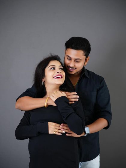 A happy, candid moment between an expecting couple during their studio photoshoot. Their smiles and loving gaze say it all.