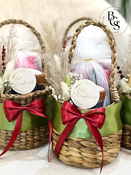 These charming mini-baskets, tied with a satin green ribbon, are a delightful way to present small return gifts. They are filled with thoughtful items and decorated with dried flowers for a rustic touch.