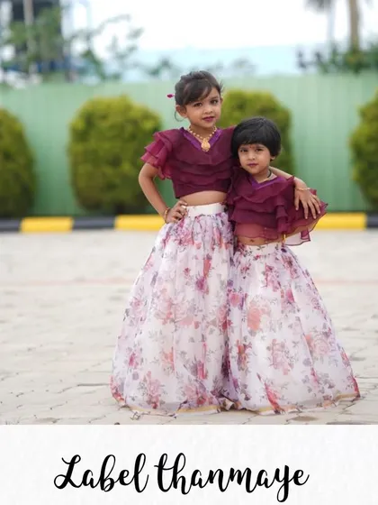 For a modern take on sibling twinning, I created this set featuring a wine-colored crop top with ruffled sleeves and a floral organza lehenga skirt. This coordinated sister outfit is perfect for weddings and festive events.