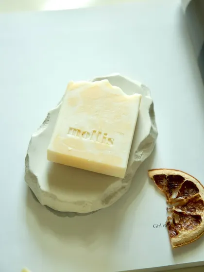 A single bar of Orange & Bergamot soap, simply styled with a dried orange slice.