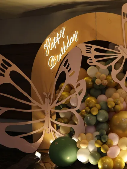 A close-up of the butterfly theme's neon 'Happy Birthday' sign and intricate butterfly wing cutouts, surrounded by a cascade of balloons.
