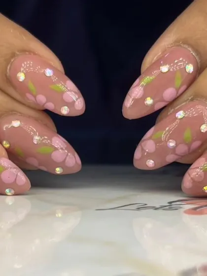 A close-up of the delicate floral and rhinestone nail art.