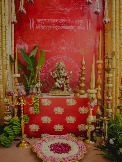 We honor tradition with beautiful, detailed setups. This sacred space for a South Indian wedding features a Ganesha idol, traditional brass lamps, banana leaves, and a floral rangoli, all against a rich, custom backdrop.
