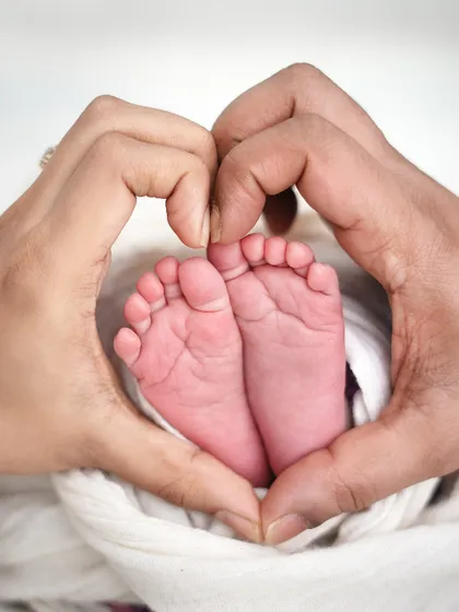 Parents' hands forming a heart shape around their baby's feet. This is a creative and sentimental way to capture those tiny details.