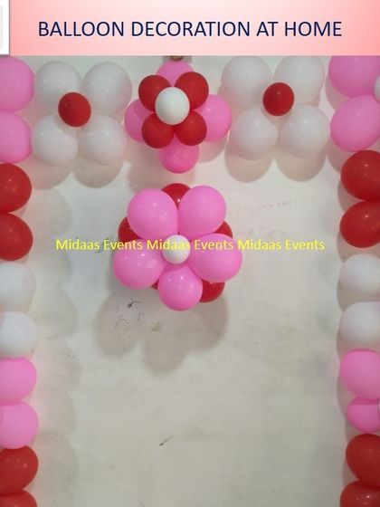 A floral-themed balloon decoration for a home party. Using balloons to create flower shapes is a creative way to decorate a wall for a birthday or baby shower.