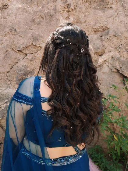 A detailed view of the engagement hairstyle. We created soft, flowing curls with a delicate braided detail and pearl accessories for a touch of elegance.