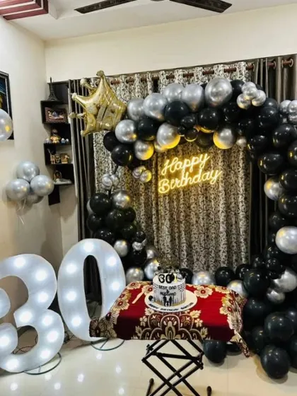 Milestone birthdays deserve a grand setup. Here's a 30th birthday party I decorated at home, featuring large marquee light numbers, a full balloon arch in black and silver, and a 'Happy Birthday' neon sign against a sequin backdrop.