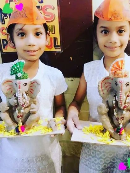 Twin sisters proudly present their matching eco-friendly Ganesha idols, each with its own unique decoration.