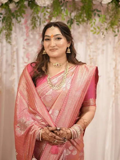 A beautiful portrait of a bride-to-be at her engagement ceremony, wearing a pink silk saree with soft, wavy hair.