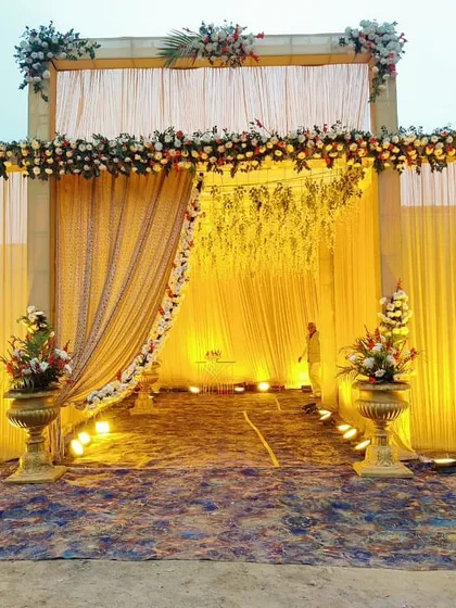 An evening shot of the same grand wedding entrance, showing how the spotlights highlight the floral decor and create a dramatic, welcoming ambiance for guests.