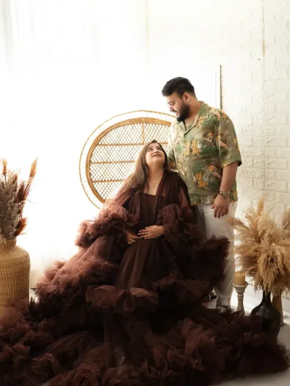 A tender moment between partners during a studio maternity shoot. The rich brown ruffled gown adds texture and elegance to this beautiful portrait against a bright, airy backdrop.