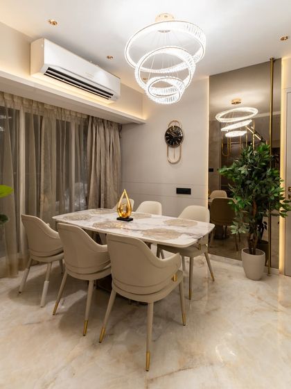 Where every meal feels like a celebration. This elegant dining space is a symphony of soft light tones, a luxe marble tabletop, and rich reflections from a stunning brown mirror, all accented with a glossy SS gold rod.