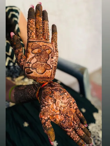 A creative pose showing both the front and back of the hands, with one featuring a Ganesh portrait and the other a traditional pattern.