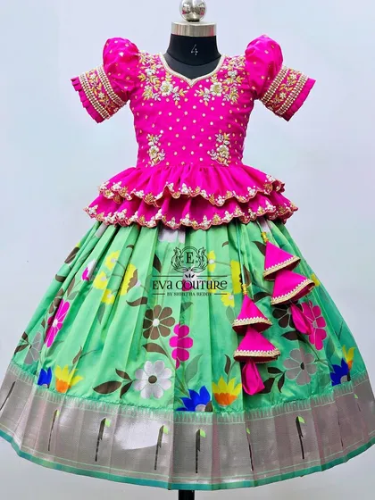 A stunning floral lehenga in green and pink. The blouse is heavily embroidered, and the skirt is made from a lightweight, printed fabric.