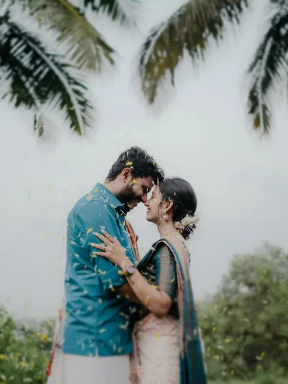 A stunning shot of the couple under palm trees, with flower petals falling around them. This image feels both epic and intimate, a perfect blend of romance and nature.
