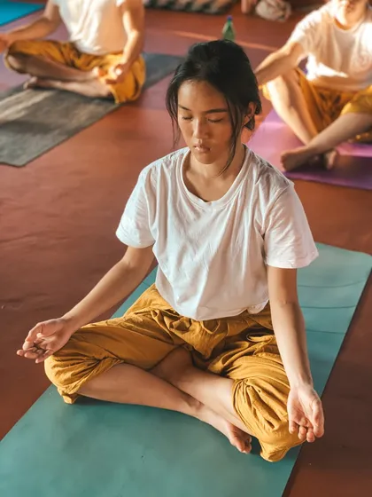 A student sits in quiet meditation, embodying the stillness and presence that we cultivate. The soft light highlights their peaceful state.