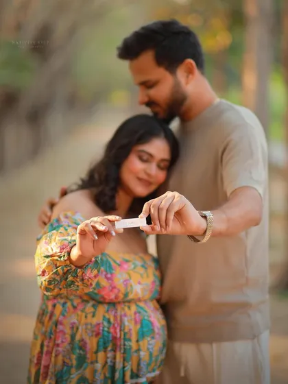 A close-up shot focusing on the pregnancy test, symbolizing the start of this incredible journey. The couple's embrace in the background adds emotional depth.