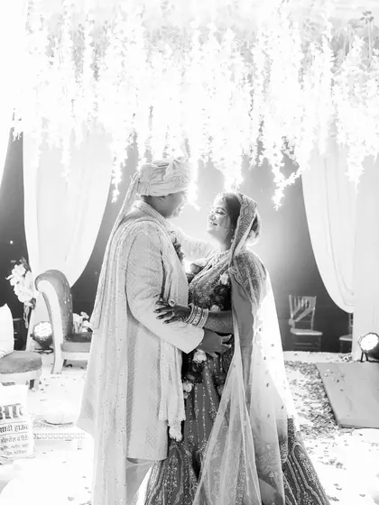 A high-key black and white portrait of the couple under a beautiful floral ceiling. This artistic style creates a dreamy, ethereal feel.