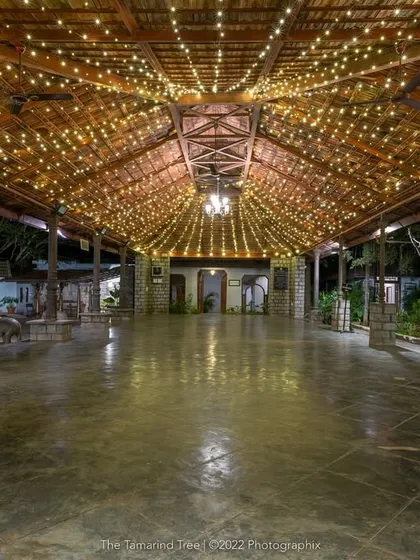 The main hall, with its high, tiled roof and stone pillars, is a grand space for dining and celebrations, shown here lit for an evening event.