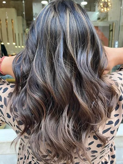 A perfect example of a sun-kissed caramel balayage on a dark base. I hand-painted these highlights to create a seamless, natural-looking blend that adds warmth and dimension. The final style with soft waves really makes the caramel tones pop.