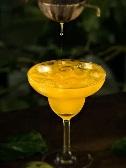 An action shot of a single drop falling into the passion fruit drink, captured with dramatic lighting to freeze the motion and create impact.