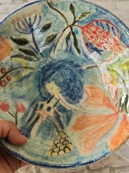 A close-up of a hand-painted plate featuring a vibrant, abstract floral design. Each brushstroke is carefully applied to create a one-of-a-kind piece of functional art for your dining table.
