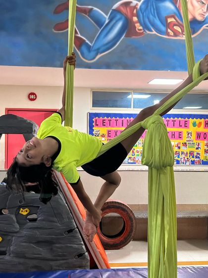 This inverted pose near the climbing wall shows a student's comfort and control while hanging upside down.