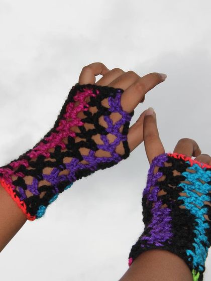Another angle of the neon and black crochet gloves. They are perfect for adding a pop of color and a punk-rock vibe to your style.
