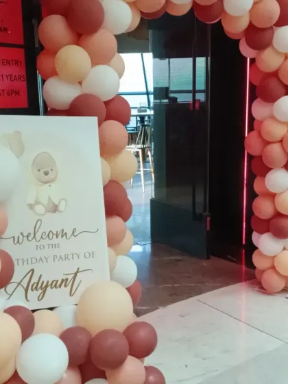 The balloon arch entrance for the teddy bear-themed party, welcoming guests with a custom sign and a warm, neutral color palette.