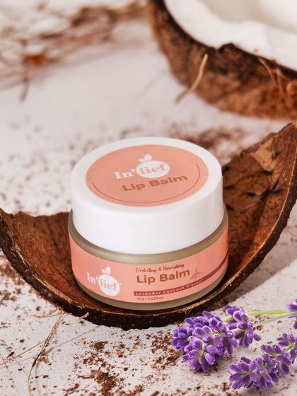 A styled shot of In'lief lip balm on a coconut shell with lavender sprigs. This composition highlights the natural coconut and lavender ingredients.