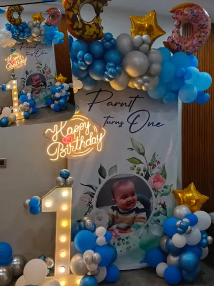 A sweet donut-themed first birthday setup. This decoration includes a custom backdrop with the baby's photo, a light-up number '1', and fun donut-shaped foil balloons.
