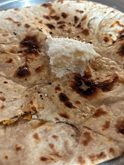 A special homemade Besan ki Tandoori Roti, topped with white butter. It's a rustic and healthy bread option.