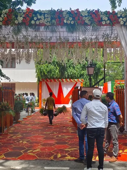 For a political leader's event, I created this entrance gate using a tricolor theme with saffron and white drapes and a dense floral border. The setup includes a clean, patterned carpet walkway and floral stands, making a professional first impression for arriving guests.