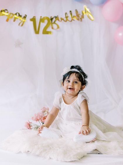A happy smile from the half-birthday girl, surrounded by pink flowers and soft tulle.