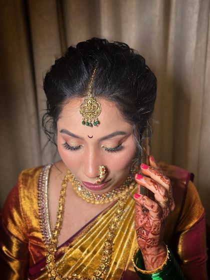 A close-up on the makeup, showing the soft eyeshadow and how it complements the intricate nath and maang tikka.