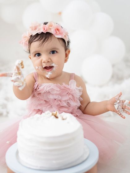 A happy baby girl enjoying her cake smash session. The pink tutu and frosting-covered hands are just perfect.