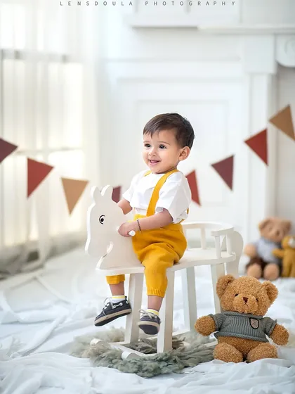 Giddy up! This little cowboy is all smiles on his white rocking horse, creating a classic and joyful portrait.