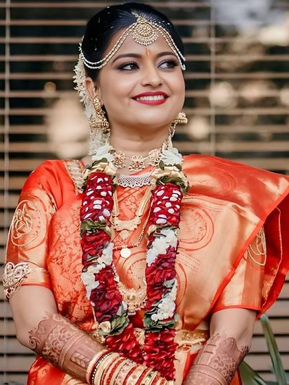 Adorned with a floral garland, this bride's makeup is warm and radiant. The red lip and bindi are classic choices that perfectly suit the traditional ceremony.