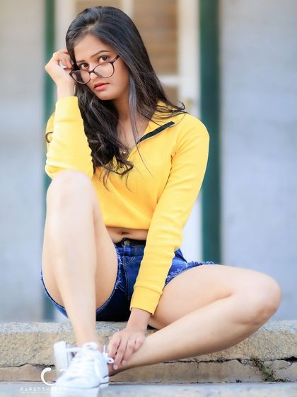 A direct and engaging portrait. The way she adjusts her glasses feels natural and adds character to the shot.
