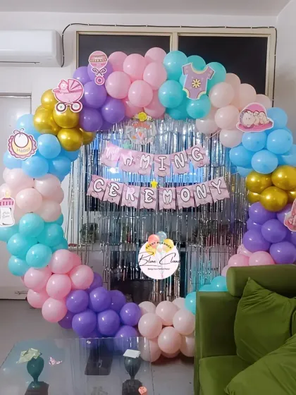 A pastel-themed naming ceremony decoration with a full balloon ring and a silver shimmer curtain.